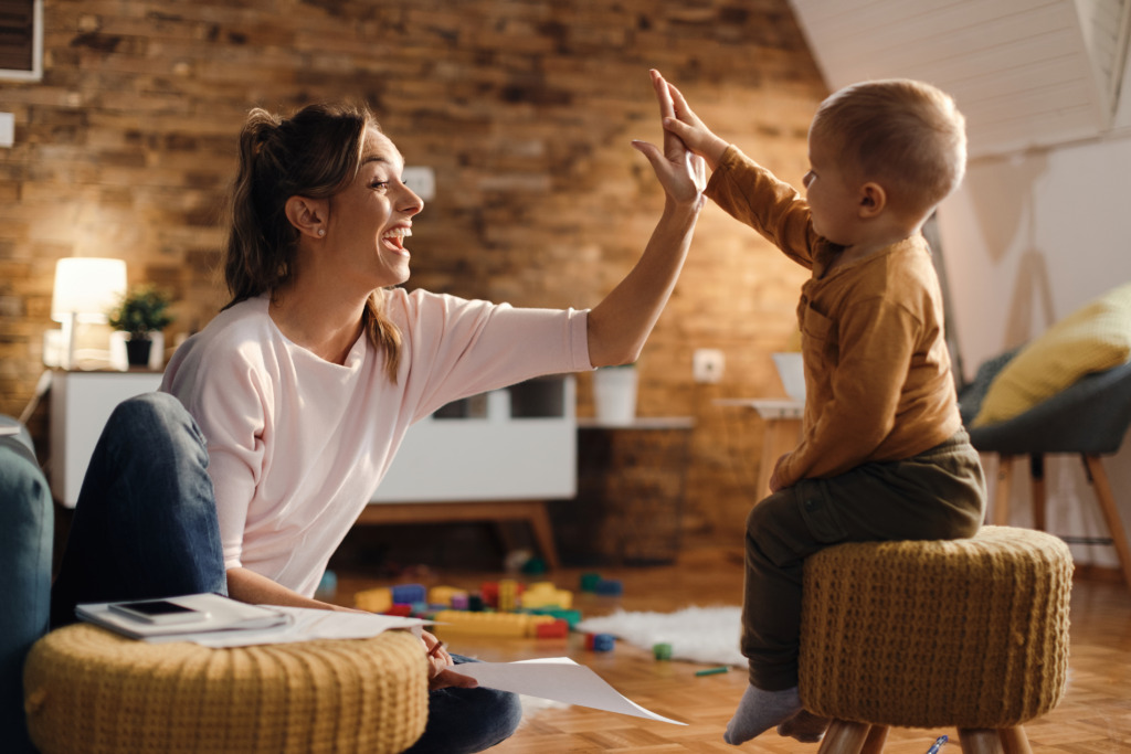Madres alfa, zen y todoterreno: ¿qué tipo de mamá eres? 1 madre alegre dando choca esos cinco su pequeno hijo en casa